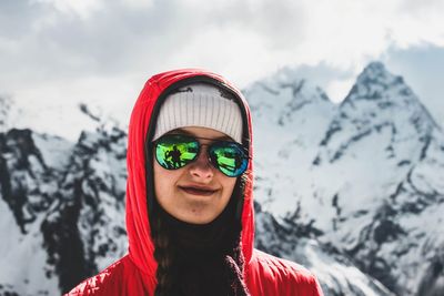 Portrait of smiling woman against snowcapped mountains during winter