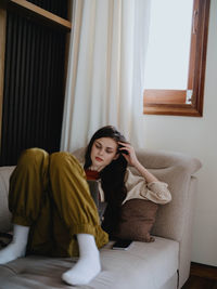 Young woman sitting on sofa at home