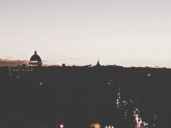 Illuminated buildings against sky at sunset