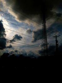 Low angle view of silhouette electricity pylon against sky