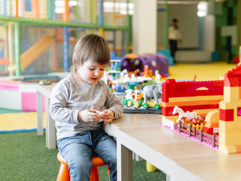 Cute boy sitting at table with toys