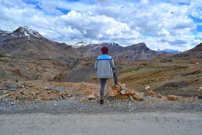 Rear view of woman standing on mountain road