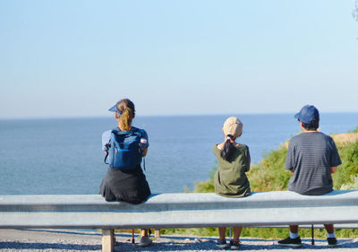 Rear view of people looking at sea against clear sky