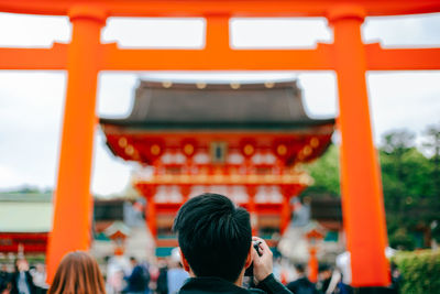 Rear view of man photographing at fushimi inari-taisha