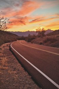 Empty road against sky during sunset