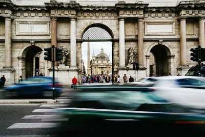 People by blurred motion of cars at piazza del popolo in city