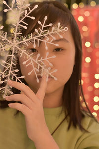 Close-up portrait of woman holding christmas decoration