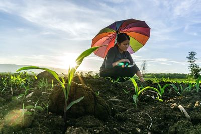 Woman under umbrella working on farm