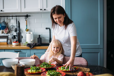 Mom and daughter together prepare dinner for a large family in the kitchen.