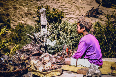 Side view of a young woman sitting outdoors