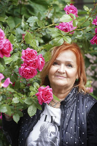 Portrait of woman by pink roses plant