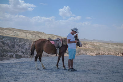 Man with horse standing on field against sky