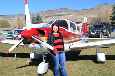 Air show. a young woman stands next to a small plane and smiles