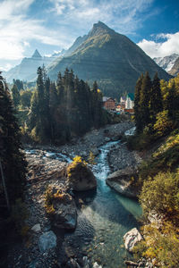 Scenic view of waterfall by mountains against sky