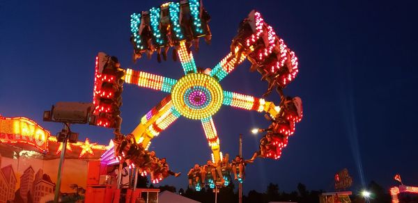 Low angle view of illuminated ferris wheel against sky at night