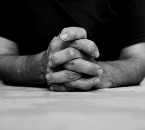 Midsection of man with hands clasped on table