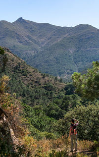 Man standing by tree in forest