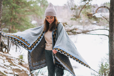 Woman wearing hat standing against snow during winter