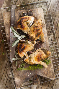 High angle view of roast chicken on cutting board with rack over wooden table