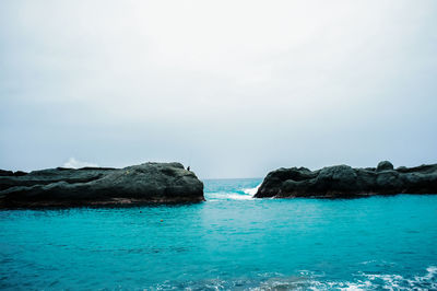 Rocks in sea against clear sky