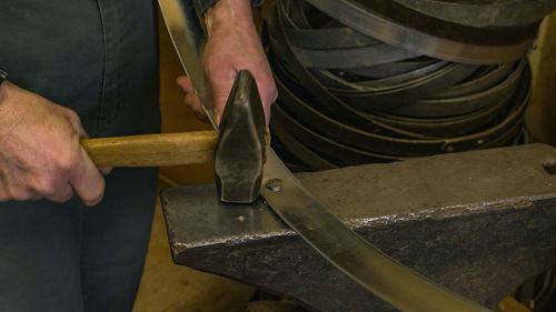 Cropped hand of man hammering metal