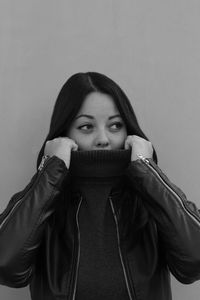 Portrait of beautiful young woman against wall