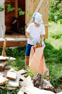 The boy collects garbage in a bag. the child will help with cleaning the territory on the street