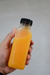 Close-up of hand holding drink against white background