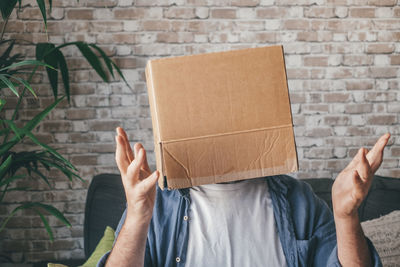 Man with cardboard box on head sitting on sofa