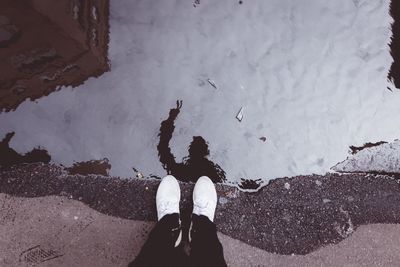 Low section of person standing by puddle with reflection