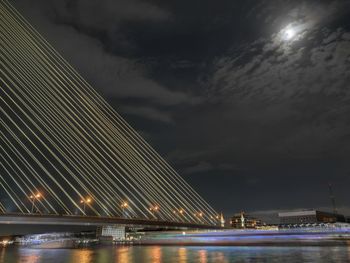 Illuminated bridge over river against sky at night