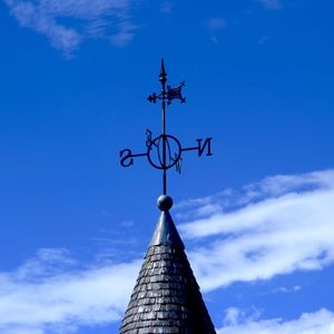 Low angle view of weather vane against blue sky