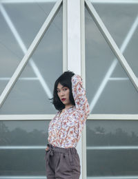 Portrait of young woman standing against railing