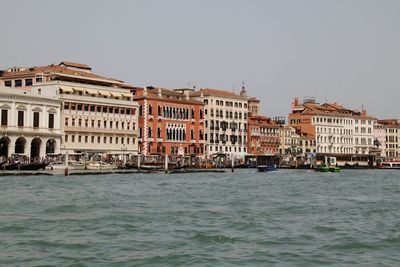 Buildings by sea against clear sky