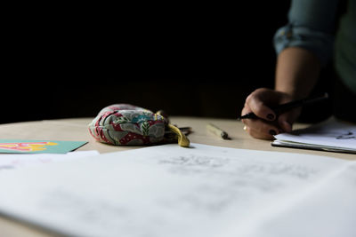 Cropped image of woman writing in book at table