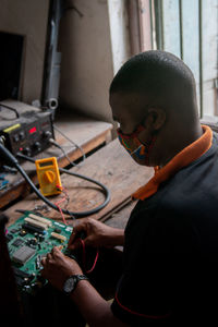 Young adult repairing a computer motherboard in a workshop