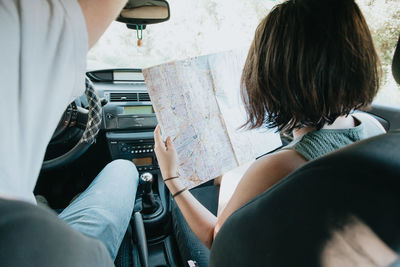 Woman holding map while sitting by man in car