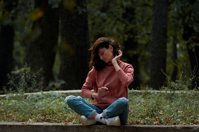 A woman in casual clothes does yoga in an old park