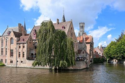 Buildings by river against sky