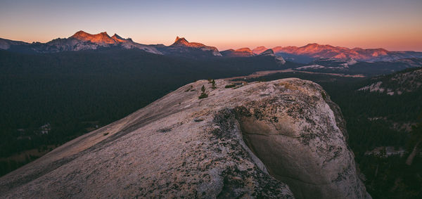 Midsection of person on landscape against sky at sunset