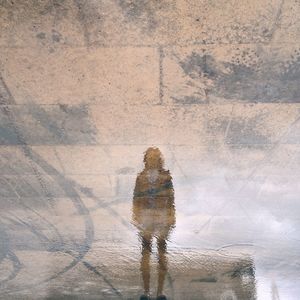 Reflection of person on water at footpath in rainy season