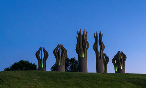 Low angle view of sculptures on field against clear blue sky