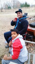 Portrait of father and son sitting on field