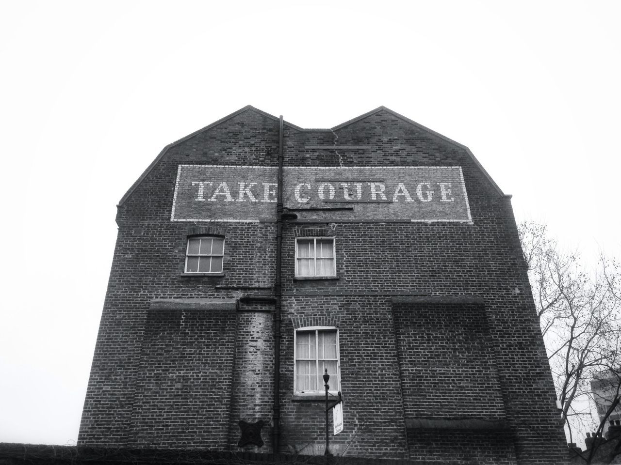 architecture, built structure, building exterior, low angle view, text, clear sky, western script, communication, building, window, sky, day, outdoors, no people, brick wall, wall - building feature, city, copy space, capital letter, old