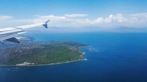 Aerial view of airplane flying over sea against sky
