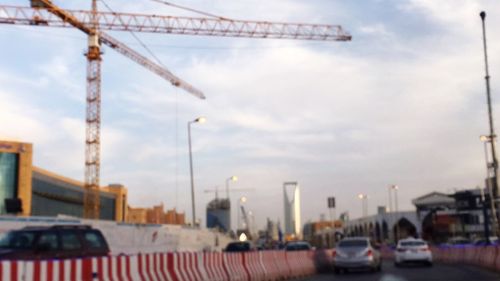 Cranes at construction site against sky in city