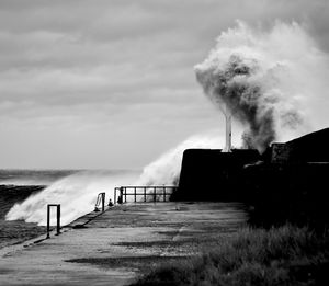 Smoke emitting from chimney by sea against sky