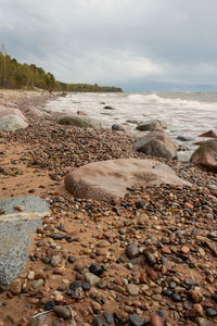 Surface level of stones on beach against sky