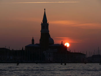 View of building by sea against sky during sunset