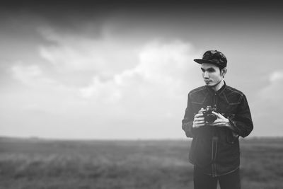 Man holding camera while looking away on field